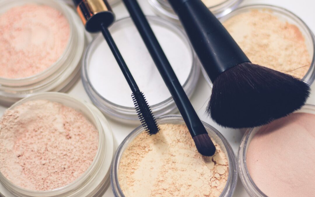 three makeup brushes on top of compact powders