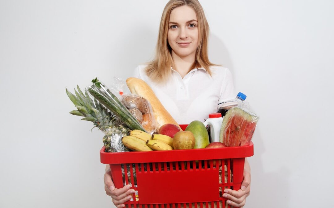 woman in white dress shirt holding red plastic basket with fruits