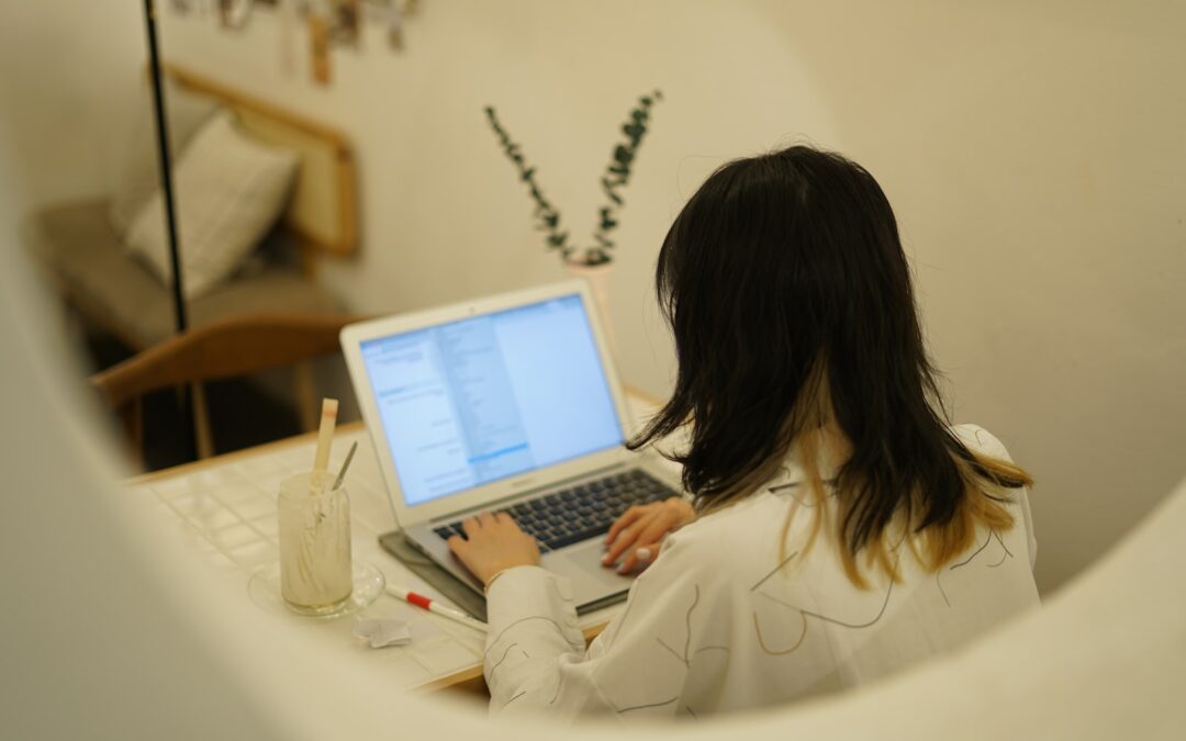 woman in white long sleeve shirt using laptop computer